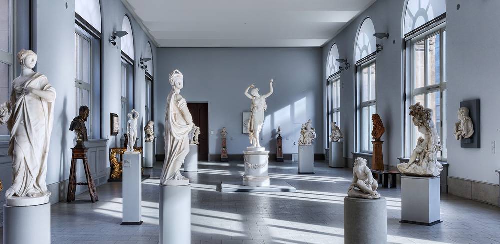 Ansicht der Sammlungspräsentation mit der „Tänzerin“ von Antonio Canova – Lichtdurchfluteter Saal mit vielen Skulpturen auf Säulen, zentrale Skulptur einer Tänzerin mit erhobenem Arm, umgeben von weiteren Kunstwerken.