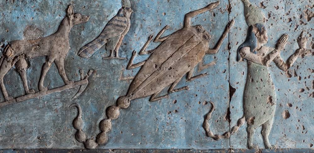 Tierkreiszeichen Skorpion auf dem rechteckigen Tierkreis von Dendera – Relief mit Mensch, Hund, Vogel und Skorpion auf blauer Wand. Mensch in klassischer Kleidung mit Kopfbedeckung, erhobene Hand. Antikes Kunstwerk.