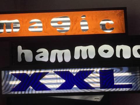  – Leuchtkasten mit den Woertern "magic" (orange Hintergrund), "hammond" (schwarz Hintergrund), "XXL" (blau auf Streifendesign).