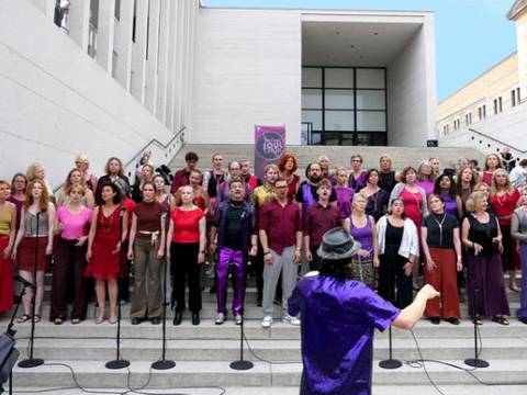 Berliner Soulchor – Gruppe von etwa 50 Sänger*innen auf einer Treppe; vorne Person mit Hut in lila Hemd. Banner mit Text: "YOUkulele: feel the joy!".