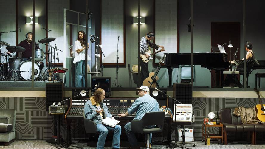 Stereophonic – Tonstudio mit Musiker*innen: Schlagzeuger, Saengerin, Bassist, Pianistin. Im Studio Regieplatz mit zwei Personen an einem Mischpult. Gitarren im Hintergrund.