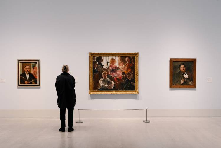 In der Ausstellung „Lovis Corinth. Dann kam Berlin!“ – Foto: Eine Person steht vor gerahmten Gemälden des Künstlers Lovis Corinth.