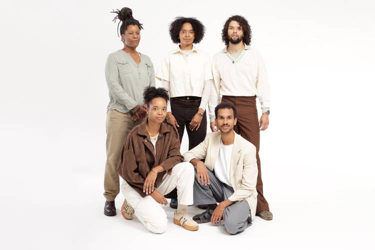 Neneh Boye & Band – Fünf Personen in lässiger Kleidung. Drei stehen, zwei hocken. Neutraler Hintergrund. Keine sichtbaren Accessoires oder bestimmte Tätigkeiten.