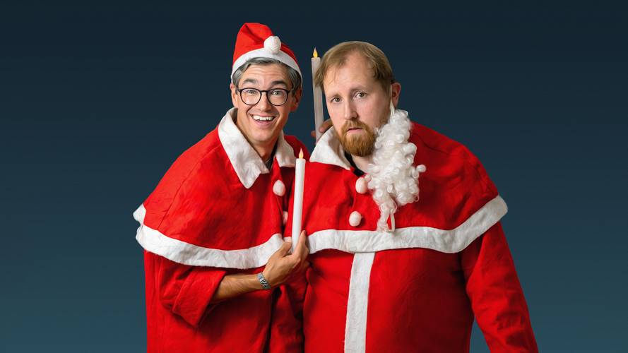 Julius Fischer & Christian Meyer – Zwei Personen in roten Weihnachtskostümen, eine mit Brille und ein Kerze haltend, die andere mit unechtem Bart. Blau-grüner Hintergrund.