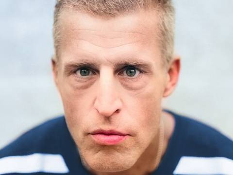 Benjamin von Stuckrad-Barre – Person mit kurzem Haar und blau-weiß gestreiftem Oberteil blickt direkt in die Kamera vor grauem Hintergrund.