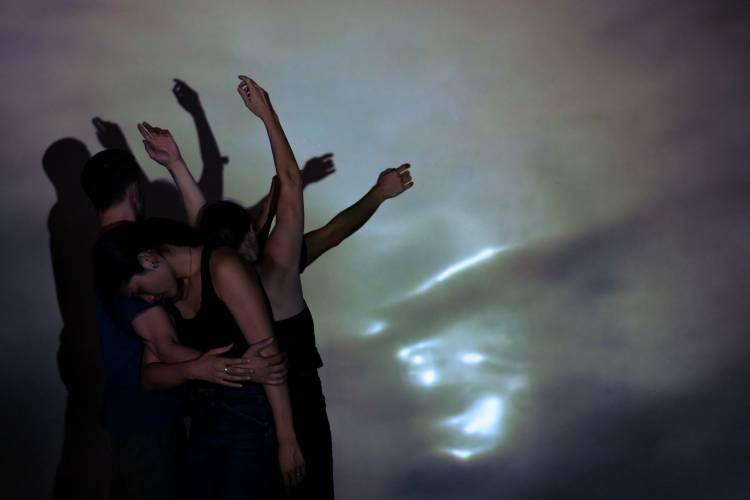 Ocean Bound 2 – Mehrere Performer*innen vor einem verschwommen beleuchteten Hintergrund, man sieht nur die erste Person, dahinter die Arme der anderen.