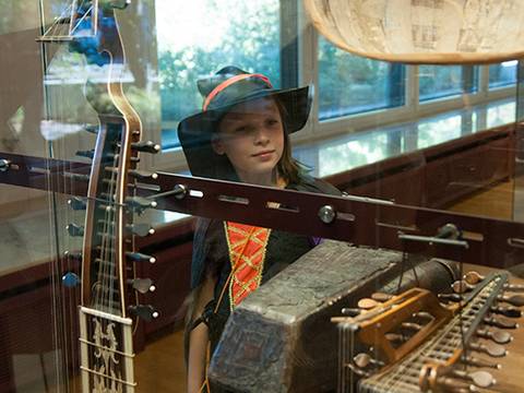 Kind in historischem Kostüm vor einer Vitrine mit Lauten – Kind in historischem Kostüm vor einer Vitrine mit Lauten