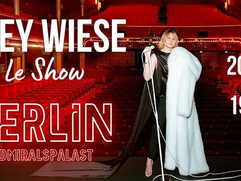  – Person mit Mikrofon und weißem Mantel im leeren Theater. Text: GREY WIESE Le Show BERLIN ADMIRALSPALAST 20/09 19:00.