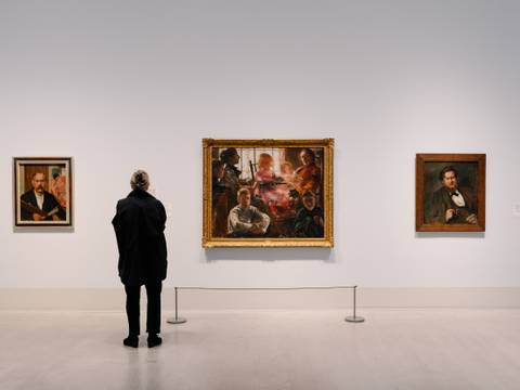 In der Ausstellung „Lovis Corinth. Dann kam Berlin!“ – Foto: Eine Person steht vor gerahmten Gemälden des Künstlers Lovis Corinth.