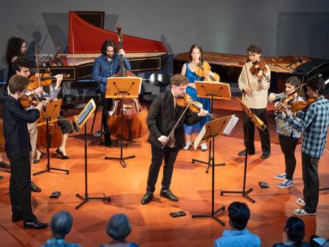 Personal Note Konzertreihe , Barenboim-Said Akademie; Foto: Peter Adamik – Gruppe von Musiker*innen spielt mit Streichen und einem Kontrabass in einem Raum mit rotem Boden, Harpsichord und Flügel im Hintergrund.