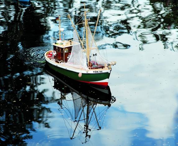 „Leinen los!“ heißt es mehrmals im Jahr im Museum: Dann tuckern kleine Modellschiffe über unseren idyllischen Museumsteich im Park. – Ein grünes Modellschiff schwimmt auf dem Teich.