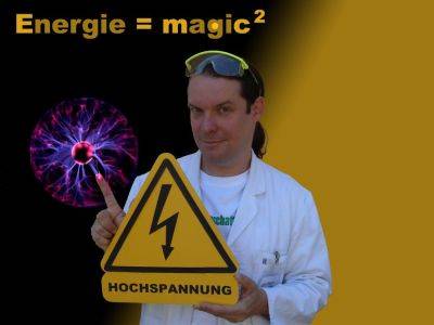 Männlich gelesene Person im weißen Kittel hält ein gelbes Schild mit Blitz und "HOCHSPANNUNG". Links eine Plasmakugel. Text: "Energie = magic²".