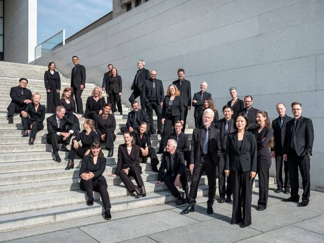 RIAS Kammerchor – Gruppe von 23 Personen in schwarzer Kleidung auf einer Treppe vor einem modernen Gebäude.