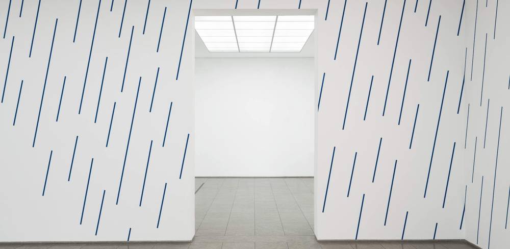 Judith Hopf, Regen #2, Detail, 2023 – Weißer Raum mit blauen, schrägen Linien an den Wänden, rechteckiger Durchgang, grauer Boden, leuchtende Decke.