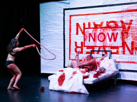 Three Times Left Is Right – Tanzende Frau in Unterwäsche mit Gedärmen und blutverschmierter Mann im Bett vor einer Plakatierung mit der Aufschrift "Now" und "Never Again".