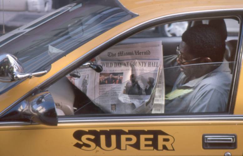 Zeitungslesender in Miami (USA), 2000 – Der Fahrer eines gelben Autos mit der Seitenaufschrift liest eine Zeitung