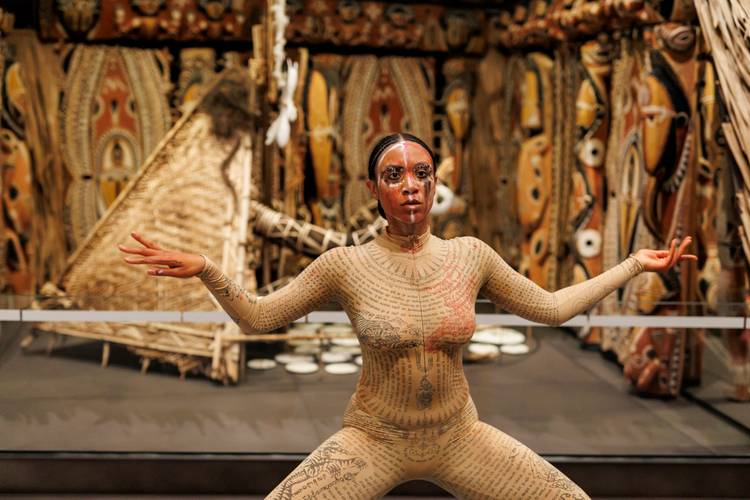 Kristy Nataraja mit einer Performance vor einem Häuserkubus aus Papua-Neuguinea – Kristy Nataraja mit einer Performance vor einem Häuserkubus aus Papua-Neuguinea