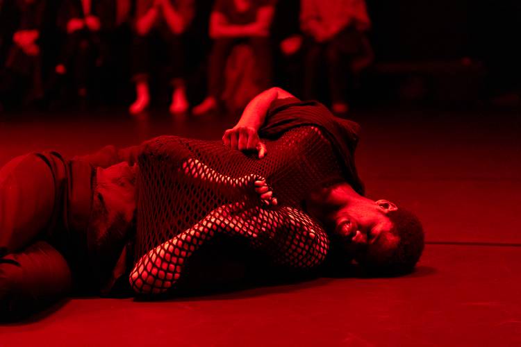 for the time being 3 – Zwei Performer*innen, die am Boden liegen, die Lichtstimmung ist rot