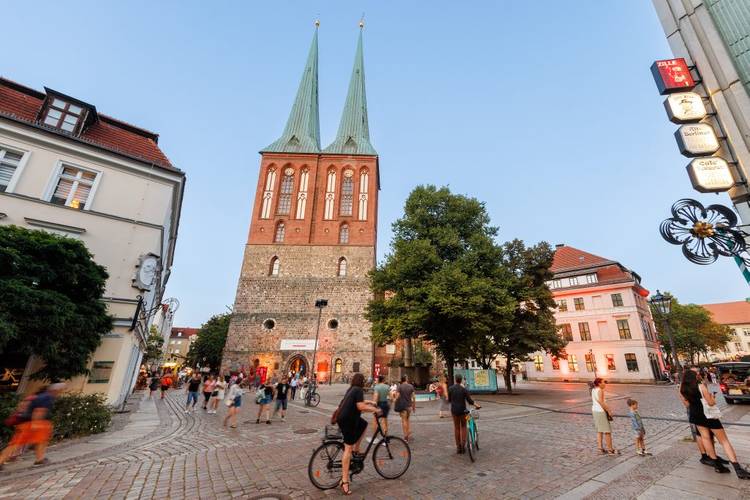 Im Herzen von Alt-Berlin: das Nikolaiviertel mit der Nikolaikirche und dem Knoblauchhaus – Foto vom Nikolaiviertel mit Blick auf die Nikolaikiche und das Museum Knoblauchhaus, Menschen sind auf der Straße