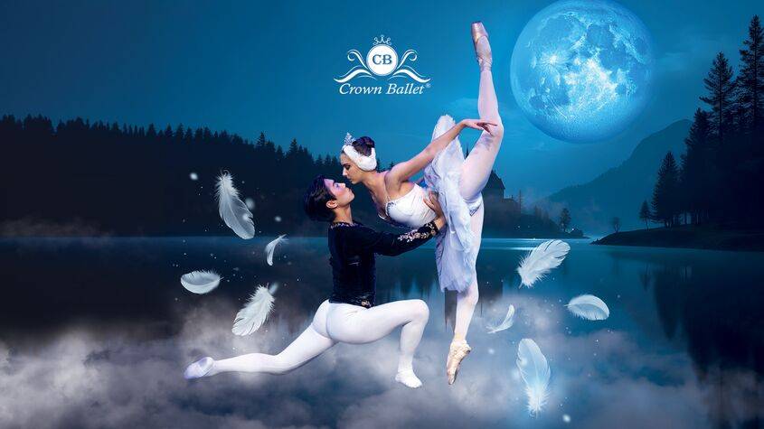 Zwei Balletttänzer*innen, eine hebt die andere, umgeben von Federn vor einem See bei Vollmond. Text: CB Crown Ballet.