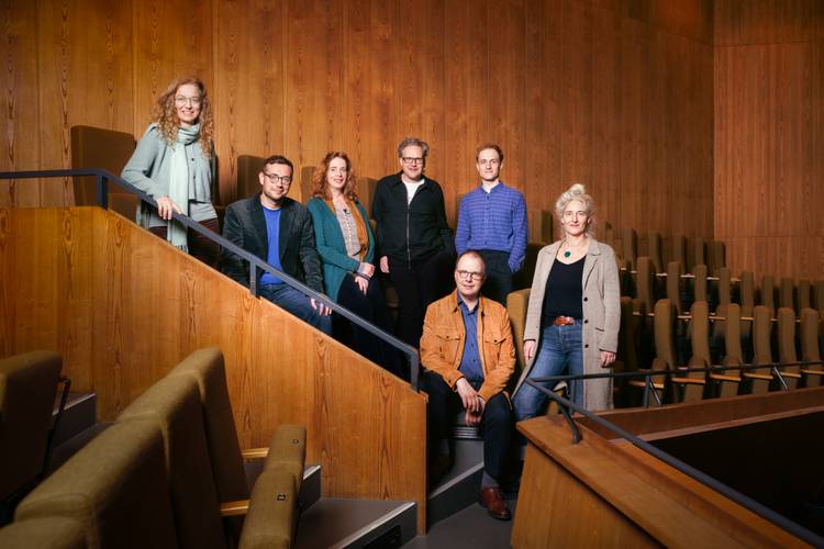 Die Theatertreffen-Jury 2026: Alexandra Kedves, Martin Thomas Pesl, Sabine Leucht, Falk Schreiber, Vincent Koch, Sascha Westphal, Christine Wahl – Die sieben Theatertreffen-Jurymitglieder stehen oder sitzen im Rang eines Theaters und schauen in die Kamera.