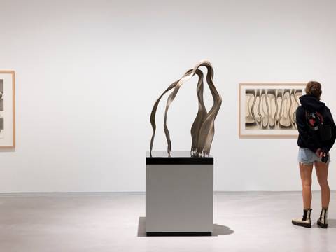 Ausstellungsansicht „Brigitte Meier-Denninghoff. Skulpturen und Zeichnungen 1946-1970“, Berlinische Galerie – Foto: Rückansicht einer Person, die vor einer Zeichnung und neben einer Skulptur von Brigitte Meier-Denninghoff im Ausstellungsraums steht.