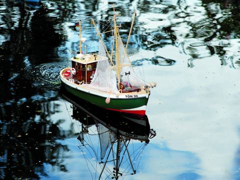 „Leinen los!“ heißt es mehrmals im Jahr im Museum: Dann tuckern kleine Modellschiffe über unseren idyllischen Museumsteich im Park. – Ein grünes Modellschiff schwimmt auf dem Teich.