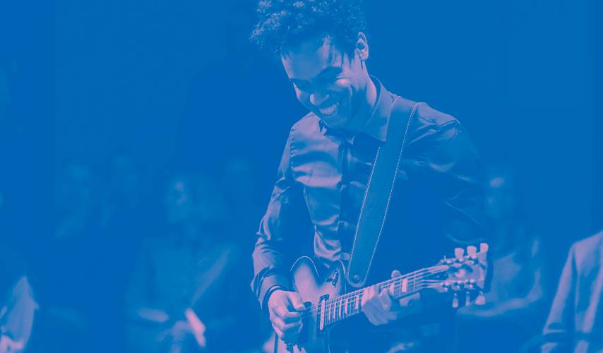 Key Visual Resident Music Collective – Lachende Person spielt E-Gitarre vor Publikum, blauer Farbstich.