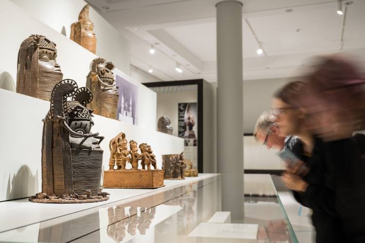 Besucher vor den Benin-Bronzen im Ausstellungsbereich "Geschichte des Königreichs Benin" im Ethnologischen Museum – Besucher vor den Benin-Bronzen im Ausstellungsbereich "Geschichte des Königreichs Benin" im Ethnologischen Museum