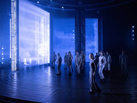 Nathan der Weise – Ein Schauspielensemble steht in gespannter Haltung auf einer blau ausgeleuchteten Bühne.