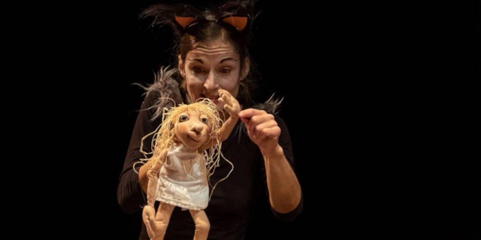 Die Zeitdiebe – Person mit Katzenohren-haarreif hält blonde Puppe mit weißem Kleid vor schwarzem Hintergrund.