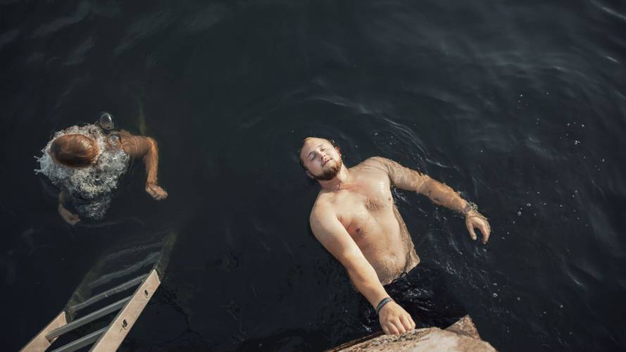 Malte aus der Serie „Bleiben“ – Ein junger Mann in Badehose schwimmt auf dem Rücken.