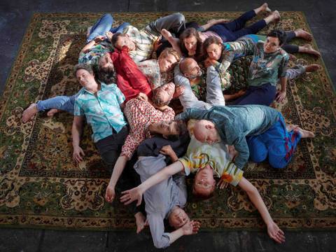 Volker Heyn: TRANSFER 1 – Gruppenbild der Mitglieder des ensemble mosaik: alle Personen liegen über- und untereinander auf einem großen Teppich