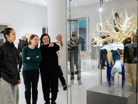 Eröffnung der Wechselausstellung "Sich verwandt machen" – Drei Personen bewundern ein kunstvolles Objekt in einer Galerie, umgeben von anderen Besuchern.