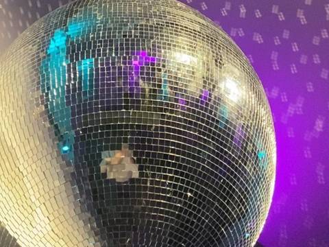  – Große Spiegelkugel vor lila Hintergrund, reflektiert Lichtpunkte und Farben in Blau und Lila.