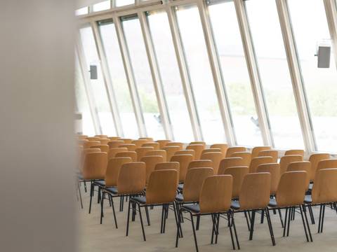  – Stuhlreihen vor einer großen Fensterfront