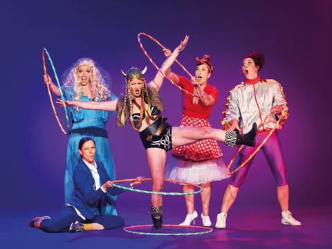Barbaren Barbies: A wild women circus – Fünf Personen mit Hula-Hoop-Reifen posieren bunt gekleidet vor lila Hintergrund; eine trägt Wikingerhelm, eine andere ein blaues Kleid.