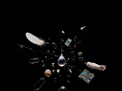  – Kristalle, Feder, Wassertropfen, mehrere Glühbirnen, Computerchip und gemalte Hand vor schwarzem Hintergrund, radial angeordnet.