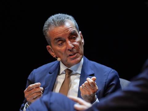 01 Friedman klein naeher – Männlich gelesene Person im Anzug, hält Vortrag, trägt Mikrofon am Ohr, dunkler Hintergrund.