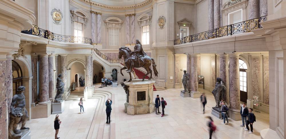 Die Große Kuppelhalle des Bode-Museums heute – Innenraum einer prunkvollen Halle mit Reiterstatue aus Bronze im Zentrum. Mehrere Personen betrachten die Kunstwerke und Architektur.