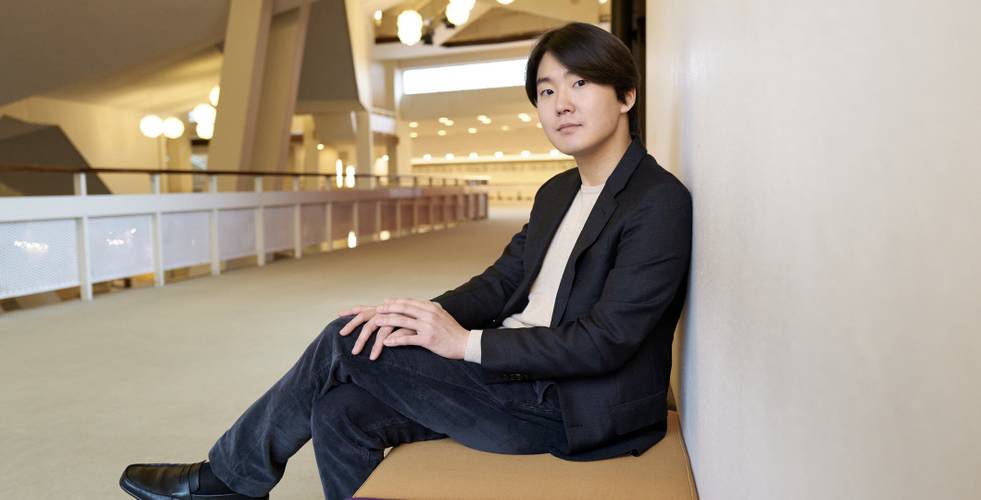 Seong-Jin Cho sitzt auf einer Bank in der Philharmonie Berlin