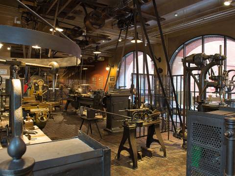Die historische Werkstatt zeigt die musterhafte Ausrüstung eines Metallbearbeitungsbetriebs um 1900. – Ein Blick in die historische Werkstatt: Hier stehen verschiedene Maschine zur Metallbearbeitung. Oben an der Decke sind die verschiedenen Räder und der Transmissionsriemen zu sehen, die die Maschinen durch eine Dampfmaschine antreiben.
