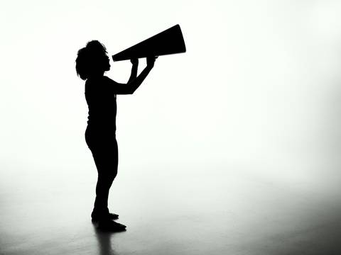Patrick Fore – Unsplash – Silhouette einer Person in Seitansicht mit Megafon in heller Umgebung.