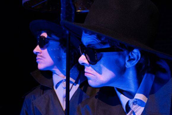 Person mit Sonnenbrille und Hut, zweimal im Bild durch Spiegelung, in blauem Licht.