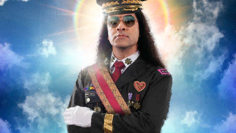 Person mit langer schwarzer Haarpracht in Uniform mit goldener Kappe und Orden, darunter "Deluxe Captain" und ein Regenbogen. Hintergrund aus Wolken und
