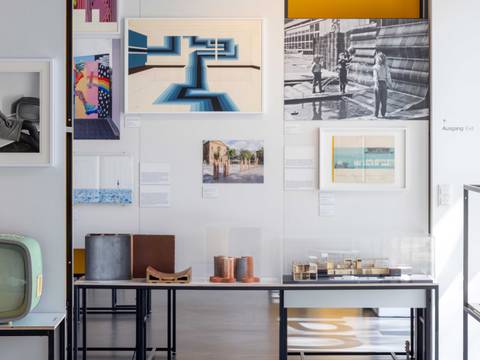 Ausstellungsansicht „Gestalten für Berlin. Design aus der Kunsthochschule Berlin-Weißensee“ – Ausstellungsansicht mit Architekturmodellen, Fotografien und Grafiken an einer weißen Wand neben einem historischen Fernsehgerät