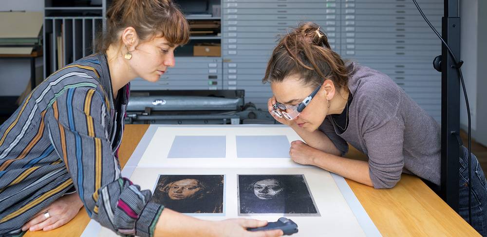 Die Restauratorinnen Tabea Harney und Antje Penz untersuchen zwei Lithographien von Käthe Kollwitz.