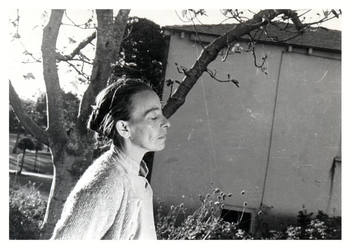 Helene Weigel Film Pressefoto – Person im Profil mit geschlossenem Auge, im Hintergrund ein kahler Baum und ein Gebäude.