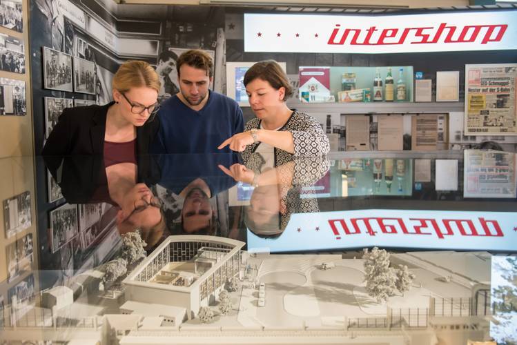 Besucherinnen und Besucher am Modell des Tränenpalastes – Eine Gruppenbegleiterin erklärt das Modell des Tränenpalastes