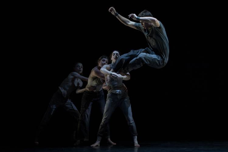 North of Now – Drei Künstler*innen halten sich aneinander in einer Reihe fest. Vorne springt ein:e Künstler*in in die Arme der ersten Person.